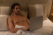 Mann benutzt Laptop im Schlafzimmer zu Hause — Stockfoto