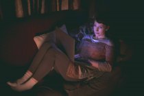 Femme utilisant un ordinateur portable sur le canapé dans le salon à la maison — Photo de stock