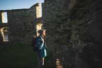 Молодой турист, стоящий в старых руинах в сельской местности под солнечным светом — стоковое фото