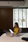 Деловая женщина сидит кровать с документами во время работы на ноутбуке в отеле — стоковое фото