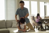 Father combing her daughters hair in living room at home — Stock Photo