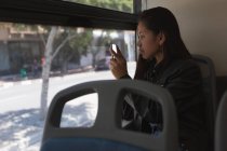 Teenage girl taking photo with mobile phone in the bus — Stock Photo