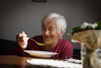 Усміхнена старша жінка снідає вдома — стокове фото