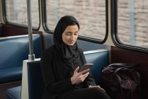 Jeune femme dans le hijab en utilisant le téléphone mobile — Photo de stock