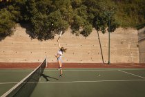 Mulher praticando tênis no campo de tênis em um dia ensolarado — Fotografia de Stock