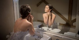 Bride getting ready in front of the mirror at home — Stock Photo