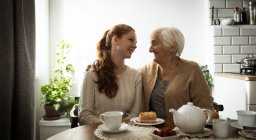 Lächelnde Großmutter und Enkelin, die sich im Wohnzimmer anschauen — Stockfoto