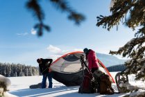 Couple pitching tent in snowy landscape during winter. — Stock Photo
