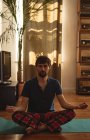 Homem praticando ioga na sala de estar em casa — Fotografia de Stock