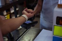 Cropped view of customer making payment through smartwatch. — Stock Photo