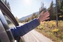Donna che sventola la mano dal finestrino dell'auto mentre viaggia — Foto stock
