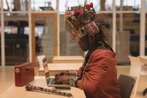 Maasai man in traditional clothing using laptop in shopping mall — Stock Photo