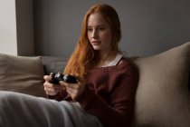 Jeune femme jouant à des jeux vidéo à la maison — Photo de stock
