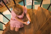Высокий угол обзора девушки с помощью мобильного телефона на лестнице — стоковое фото