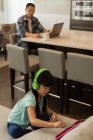 Mädchen mit digitalem Tablet, Vater mit Laptop im Hintergrund zu Hause — Stockfoto