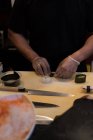 Chef rodando sushi desenrollado en una cocina de restaurante - foto de stock