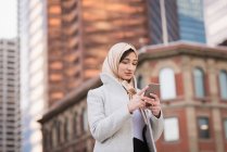 Donna in hijab utilizzando il telefono cellulare in città — Foto stock