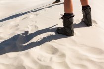 Низька частина людини, що стоїть в піску в сонячний день — стокове фото