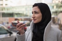 Femme en hijab parlant sur téléphone portable à la rue de la ville — Photo de stock