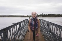 Портрет женщины в теплой одежде, стоящей на мосту — стоковое фото