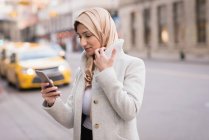 Mulher no hijab usando telefone celular na rua da cidade — Fotografia de Stock