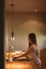 Дівчина стоїть на кухні і миє руки під водопровідною водою вдома . — стокове фото