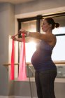 Pregnant woman exercising with resistance band at home — Stock Photo
