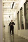 Керівник бізнесу дивиться на смарт-годинник, маючи каву в офісному коридорі — стокове фото