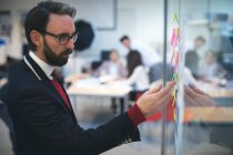 Business executive looking at sticky notes in office — Stock Photo