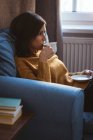 Крупный план молодой женщины, отдыхающей на диване, пьющей кофе в дневное время дома — стоковое фото