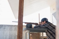 Hombre apuntando escopeta al blanco en el campo de tiro en un día soleado - foto de stock