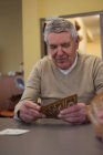 Старший чоловік грає в карти в будинку престарілих — стокове фото