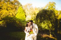 Mariée romantique et marié s'embrassant dans le jardin — Photo de stock
