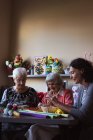 Дві старші жінки роблять штучну квітку з доглядальницею в будинку престарілих — стокове фото