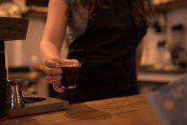 Metà sezione di barista femminile che serve caffè al bancone in caffè — Foto stock