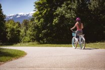 Rückansicht eines Mädchens mit Schutzhelm, das Fahrrad auf der Straße fährt. — Stockfoto