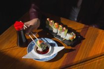 Primer plano de la mujer teniendo comida de sushi en el restaurante - foto de stock