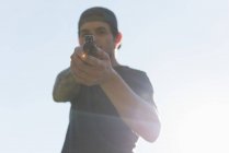 Человек, стреляющий из пистолета в солнечный день — стоковое фото