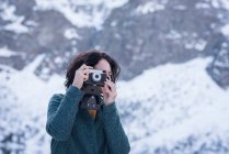 Женщина фотографируется с цифровой камерой зимой — стоковое фото