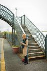 Mujer joven usando teléfono móvil en la estación de tren - foto de stock