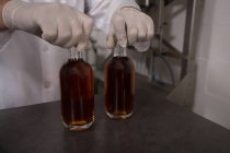 Secção intermédia do trabalhador que detém gin em garrafas na fábrica — Fotografia de Stock