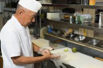 Chef sênior usando luvas de plástico na cozinha do hotel — Fotografia de Stock