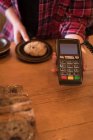 Mid section of woman holding payment terminal at counter in cafe — Stock Photo