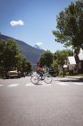 Chica montando bicicleta en el cruce de cebra en la ciudad soleada . - foto de stock
