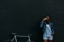 Jovem mulher tomando café contra a parede — Fotografia de Stock