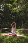 Woman practicing yoga in garden on a sunny day — Stock Photo