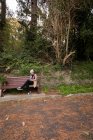 Frau sitzt auf Bank und benutzt Handy im Park — Stockfoto