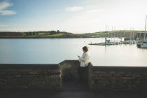 Woman using mobile phone near riverside by water. — Stock Photo