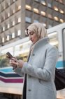Женщина в хиджабе с мобильного телефона на вокзале — стоковое фото