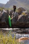 Femme tirant kayak bateau sur les rochers par la rivière . — Photo de stock